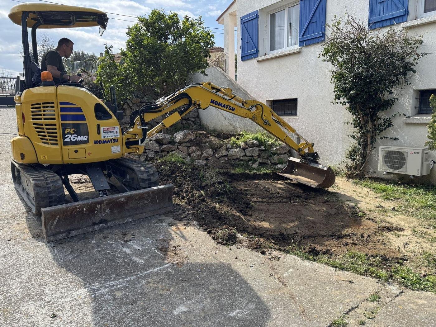 Mini-pelle au travail pendant un petit terrassement